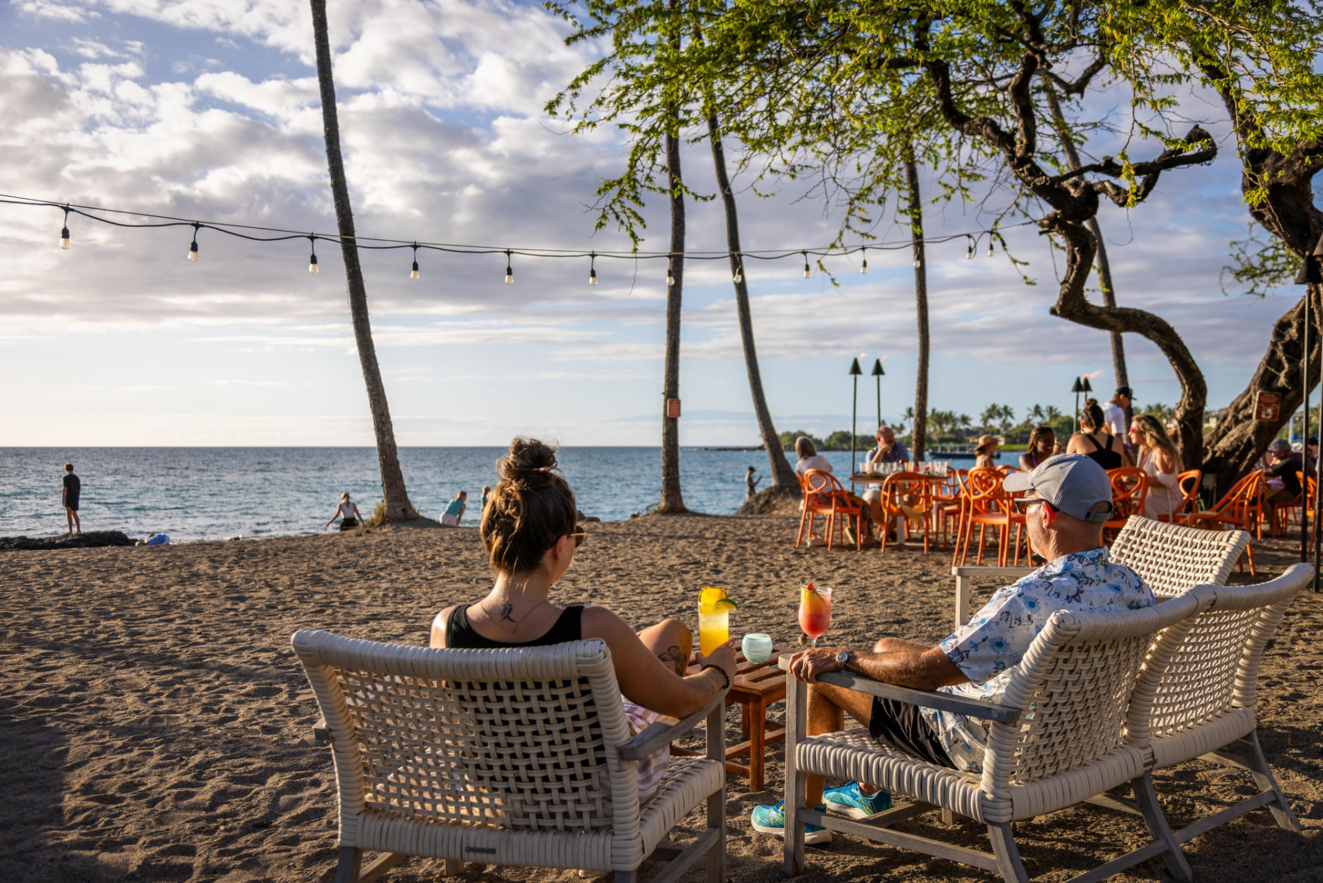 Guests relaxing in beach chairs with cocktails by the ocean